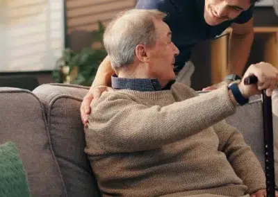 Un homme âgé assis sur un canapé avec un soignant.