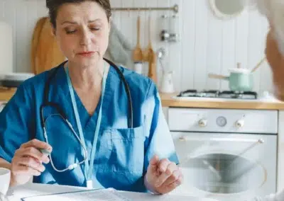 Infirmière discutant avec une personne âgée dans une cuisine.