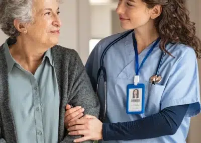 Infirmière souriante soutenant une personne âgée à domicile