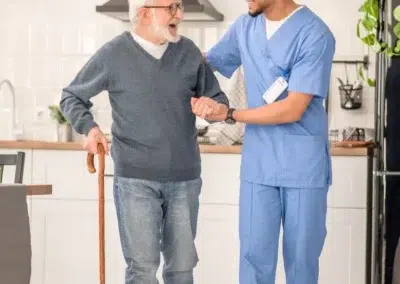 Un soignant accompagne un homme âgé dans une cuisine.
