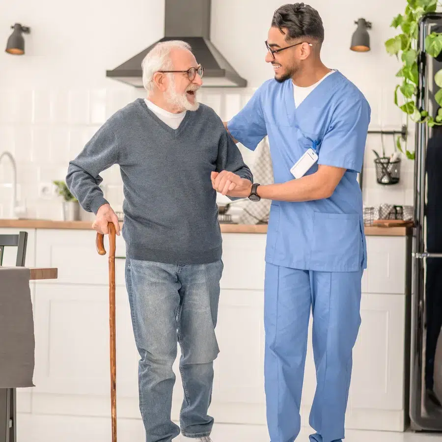 Un soignant accompagne un homme âgé dans une cuisine.