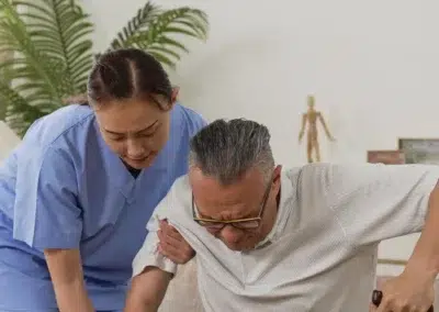 Infirmière aidant un homme âgé à se lever avec une canne.