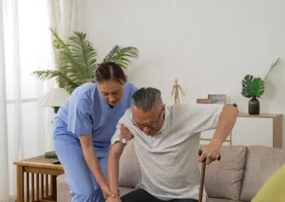 Infirmière aidant un homme âgé à se lever du canapé.