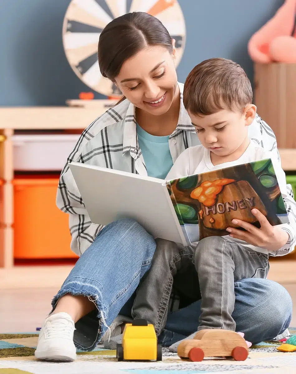 Femme lisant un livre avec un enfant dans une salle de jeux.
